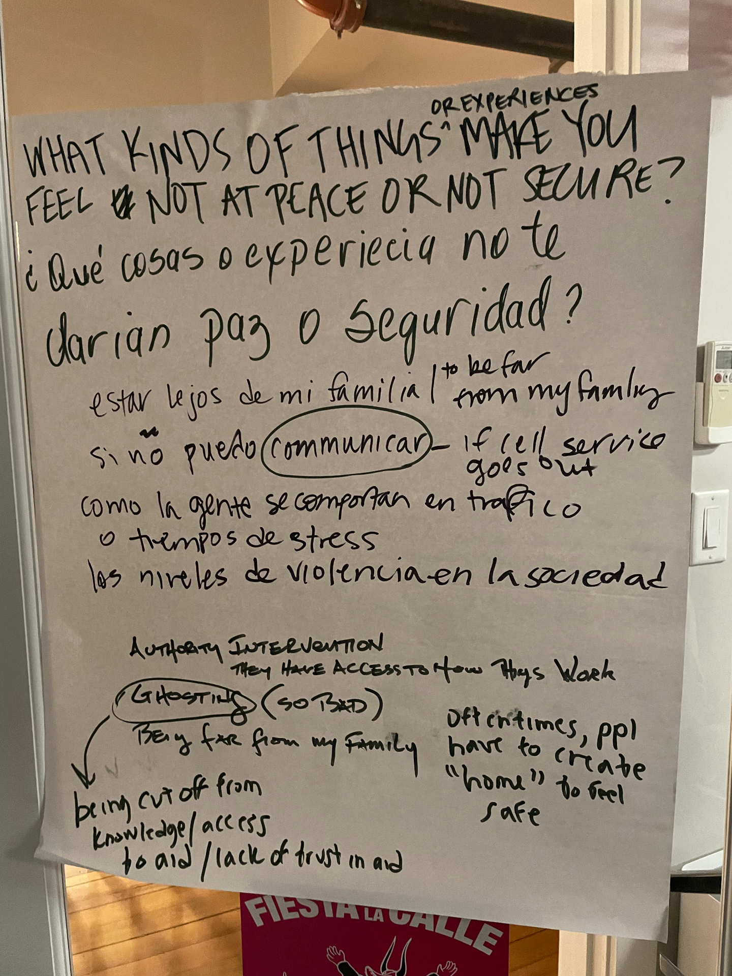 Bilingual workshop flip chart asking 'What kinds of things or experiences make you feel NOT at peace or NOT secure? / ¿Qué cosas o experiencia no te darían paz o seguridad?' covered in handwritten responses in English and Spanish about being far from family, losing cell service, ghosting, lack of trust in aid, and authority intervention.